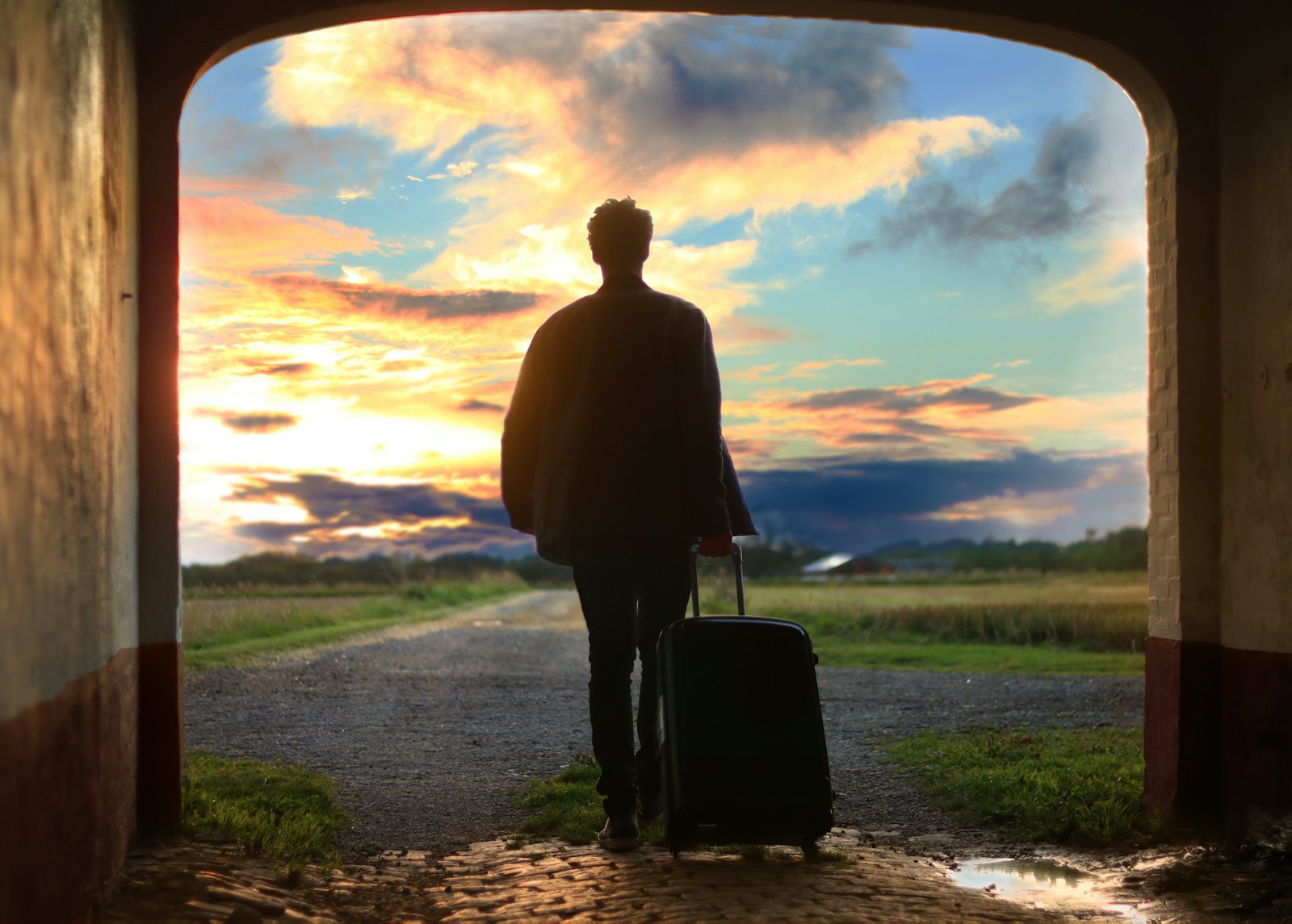 Traveller with a suitcase walking towards a golden sunset